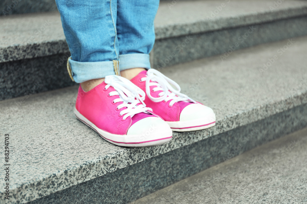Female feet in pink gumshoes on stone stairs