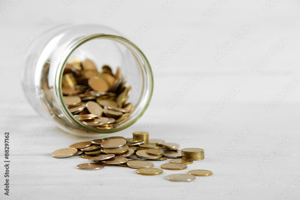 Coins in money jar on wooden background Coins in money jar on wooden background