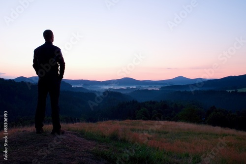Hiker stand on meadow with golden stalks of grass and watch over the misty and foggy morning valley to sunrise © rdonar