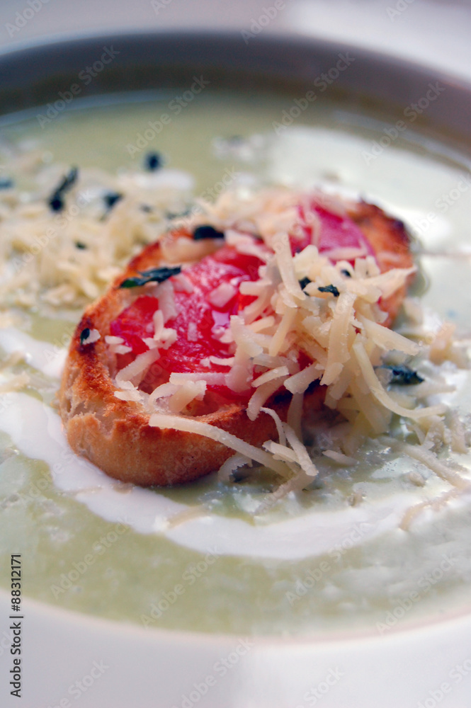 close up of green pea soup with bread and cheese on top close up of green pea soup with bread and cheese on top