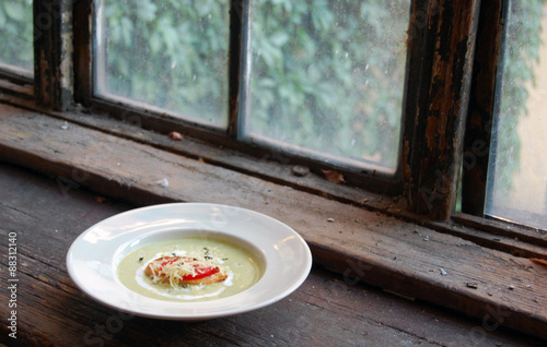 close up of green pea soup with bread and cheese on top