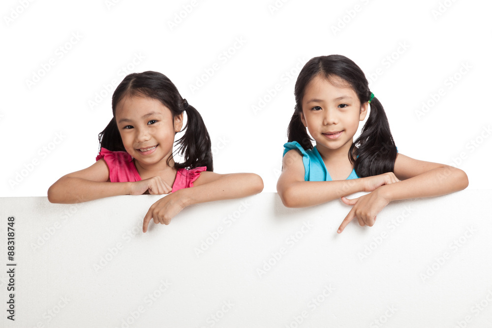 Happy Asian twins girls behind white blank banner Happy Asian twins girls behind white blank banner