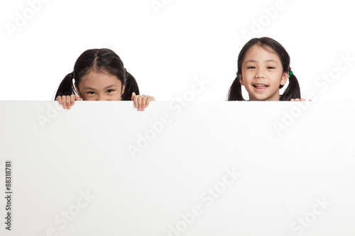 Happy Asian twins girls behind white blank banner