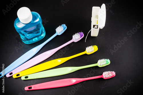 Set of colorful toothbrushs with mountwash and dental floss on b photo