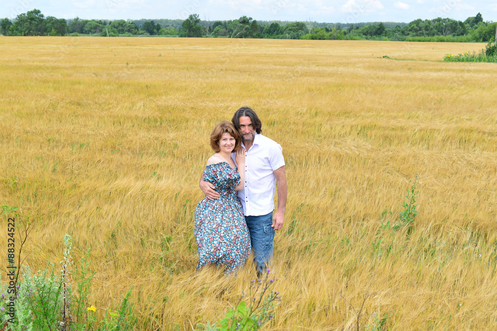 Loving middle-aged couple standing in field in summer Loving middle-aged couple standing in field in summer