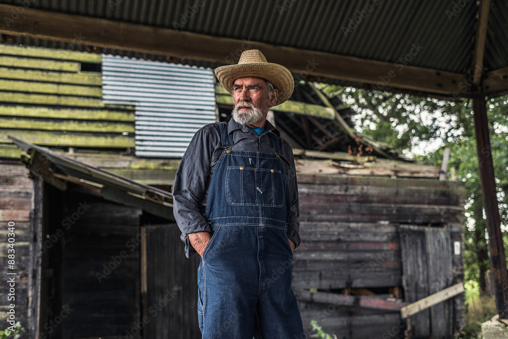 Old farmer standing in front of a rustic barn