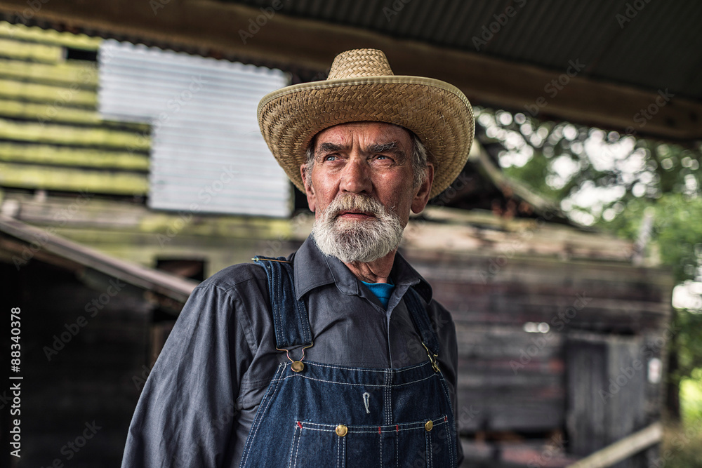 Old farmer standing in front of a rustic barn
