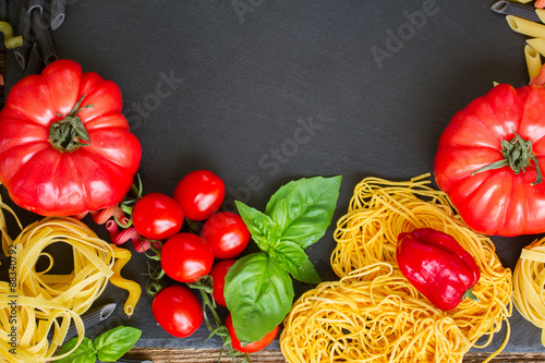 Raw pasta with ingridients on black board photo