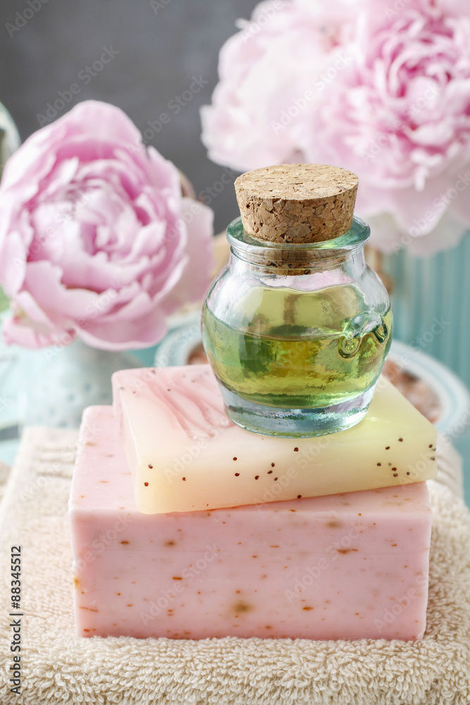 Bottle of essential oil and peonies in the background Bottle of essential oil and peonies in the background