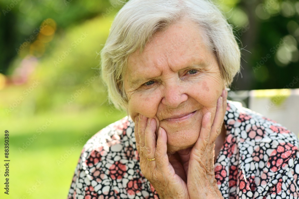 Senior woman smiling and dreaming in garden.