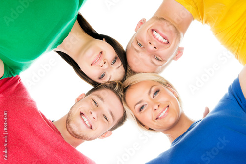 Happy students in colorful clothing standing together touching heads