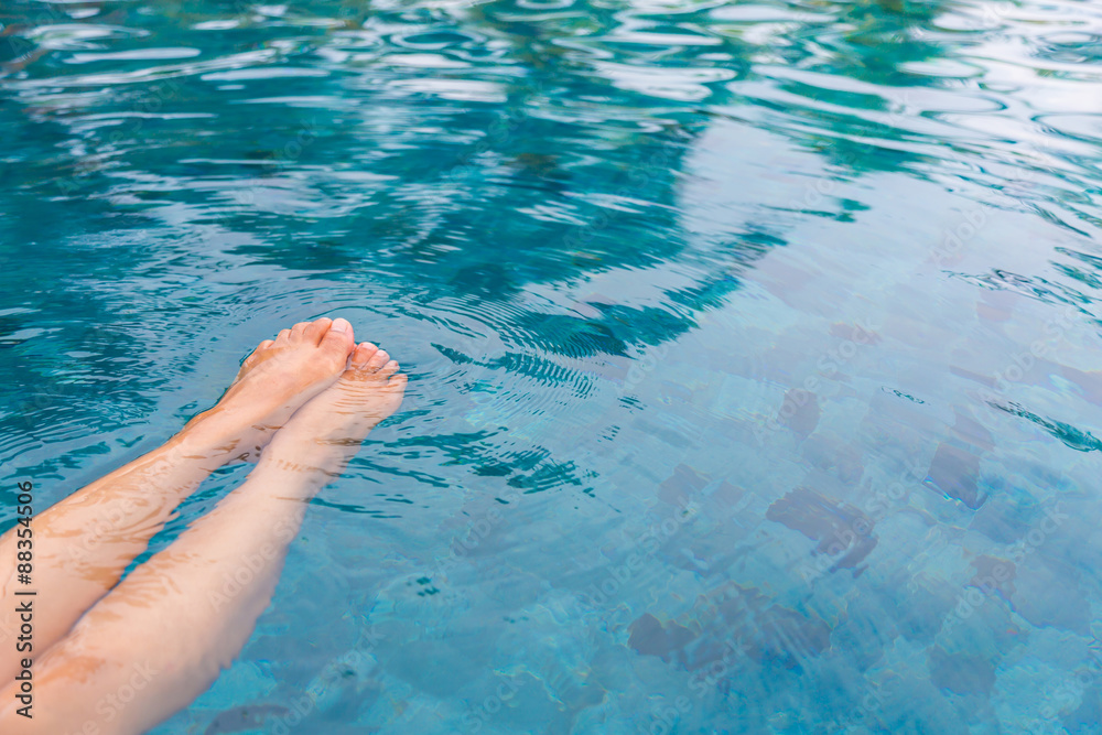Female legs in the swimming pool water