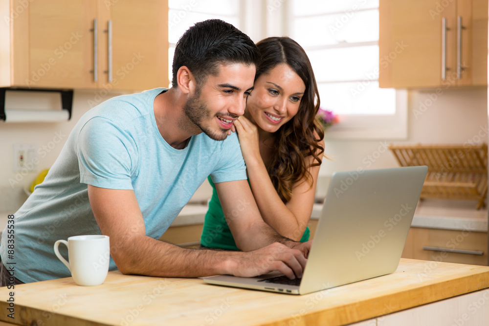 Man and woman video chat webcam with family on laptop computer social networking internet on kitchen counter Man and woman video chat webcam with family on laptop computer social networking internet on kitchen counter