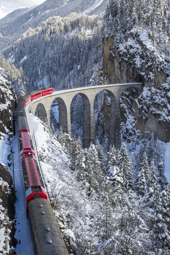 The red train of the Albula-Bernina Express Railway, UNESCO World Heritage  on the famous Landwasser Viaduct Photos | Adobe Stock