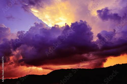 Surreal purple and red storm clouds around orange sun rays