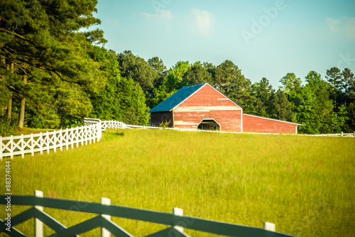 Фотография white fence leading up to a big red barn