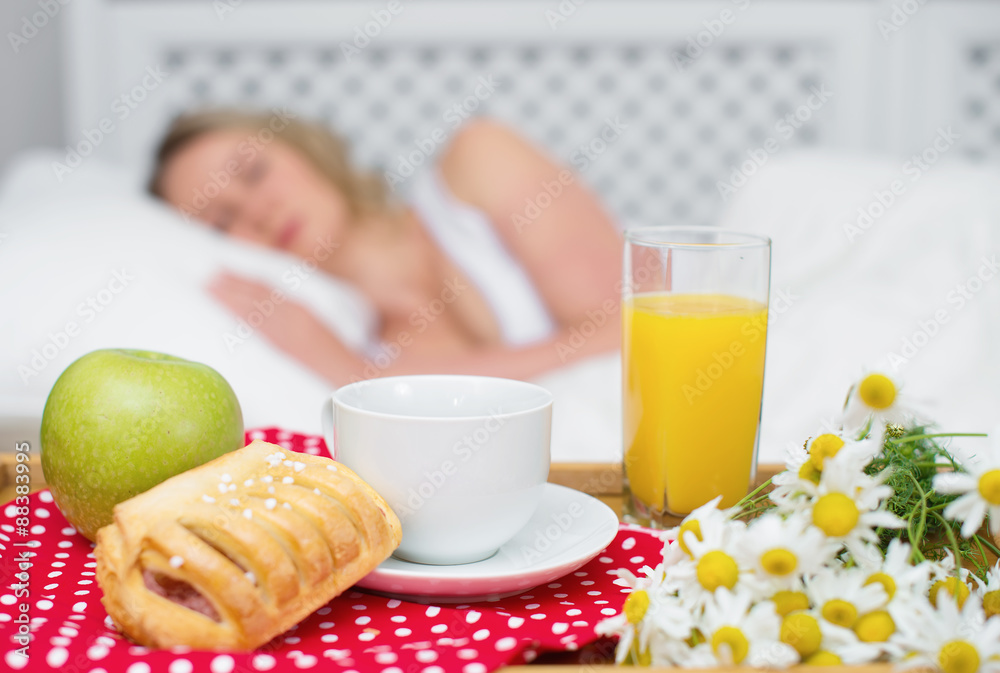 Breakfast in bed. Sleeping woman on background.