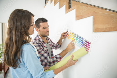 Young couple choosing paint color and pent paper photo