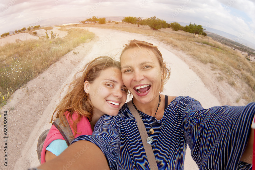two women friends doing selfie, outdoors in the fields