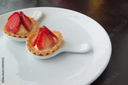 Two cheesecake with strawberries on white plate