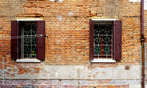 two windows with brick decay wall building