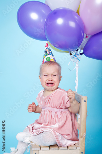 sad little girl with cap and balloons