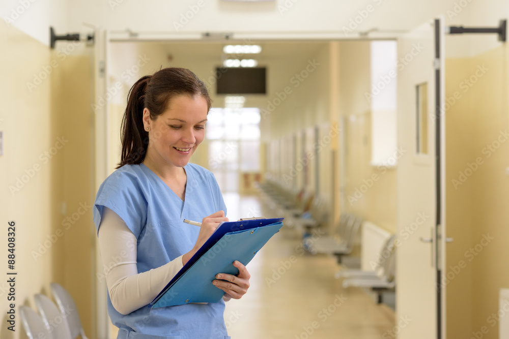 Nurse in hospital smiling and writing Nurse in hospital smiling and writing