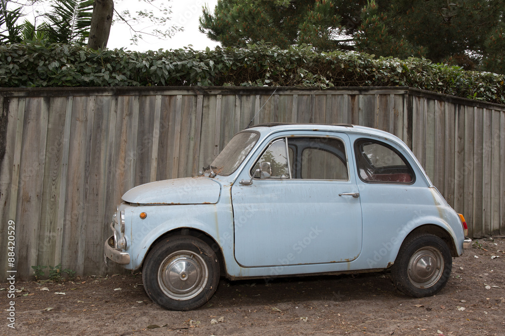 Iconic italian small Blue vintage car against wooden background