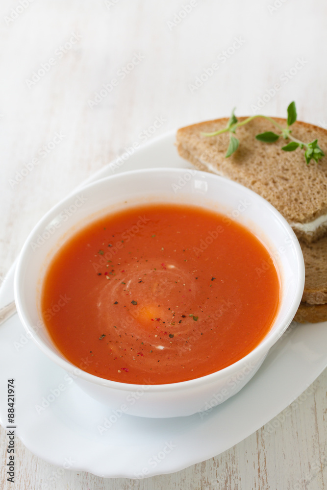 tomato soup in white bowl with sandwich on white wooden background tomato soup in white bowl with sandwich on white wooden background