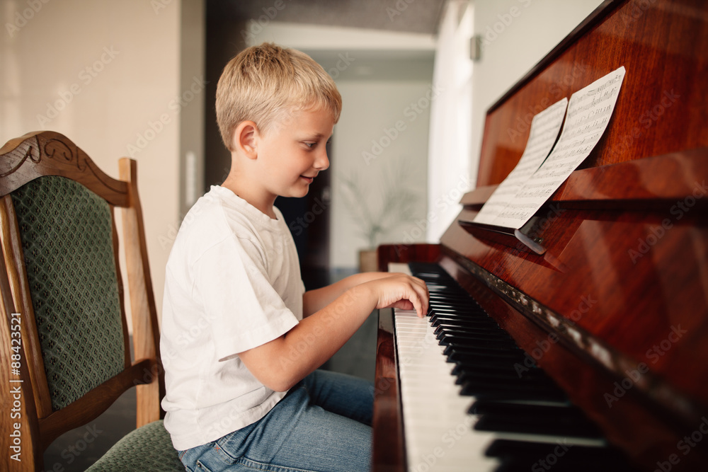 Fototapeta little happy boy plays piano