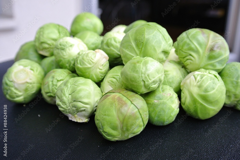 Fototapeta premium Pile of fresh green raw Brussels sprouts on the black table. Healthy/clean eating concept; organic/unprocessed food; paleo diet.