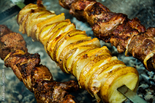 Meat and potatoes on skewers, cooked hot coals