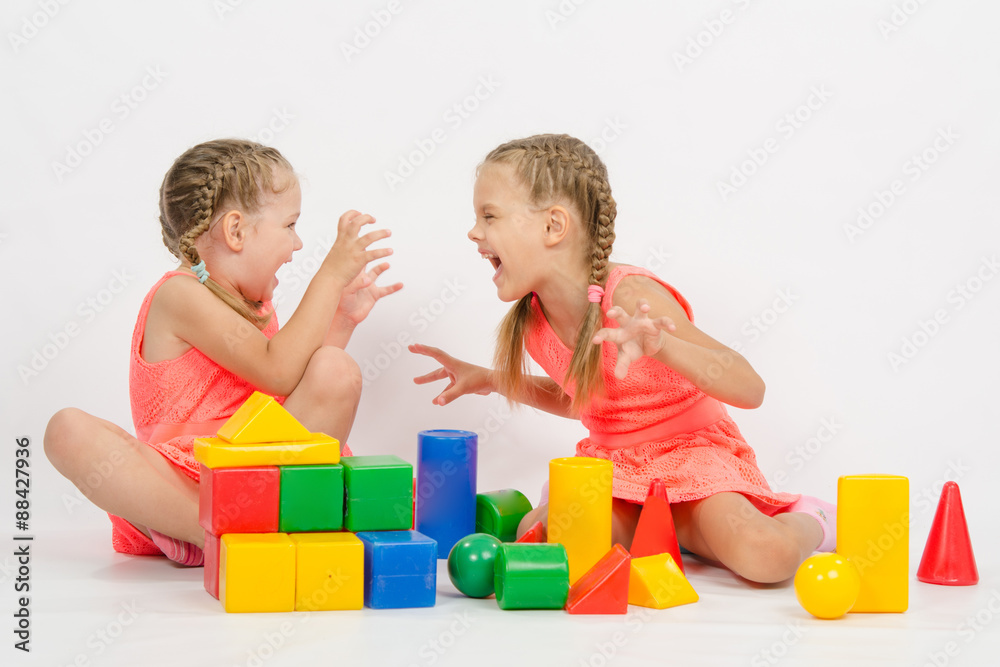 Two girls frighten each other by playing with blocks