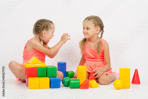 Girl frighten another girl playing with blocks