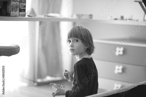 Cute serious boy sitting alone in the playroom