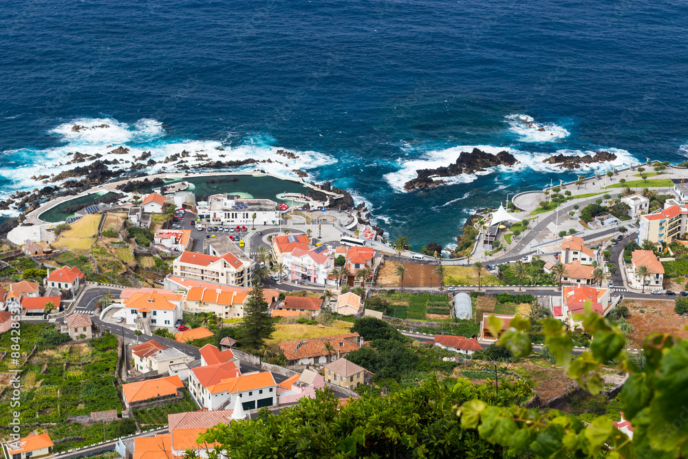 Porto Moniz village, Madeira island, Portugal. Blue sea with natural swimming pools and houses from above
