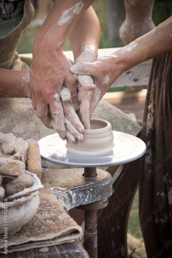 hands in the clay, four hands molded clay, the clay on a potter'