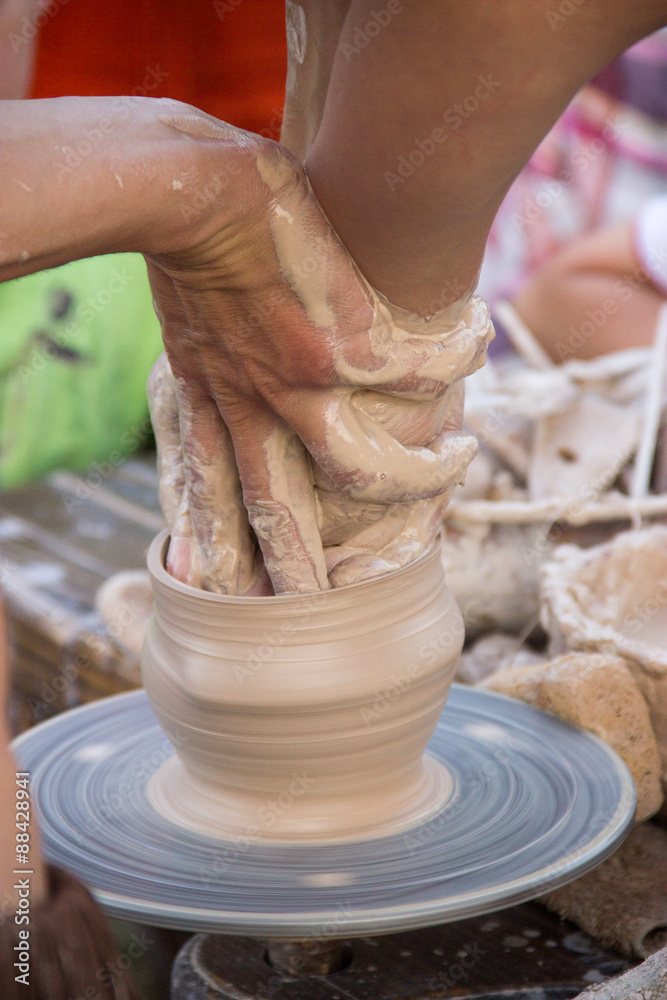 hands in the clay, four hands molded clay, the clay on a potter'