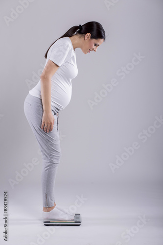 Young pregnant woman checking weight