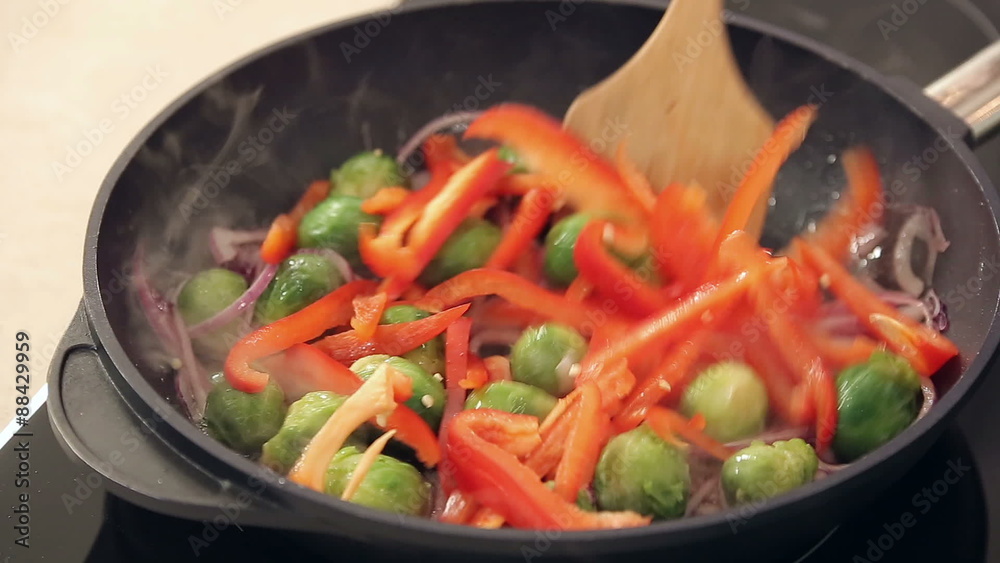 Chef is Salting Red Paprika, Brussel Sprouts and Onions Frying on a Pan Chef is Salting Red Paprika, Brussel Sprouts and Onions Frying on a Pan