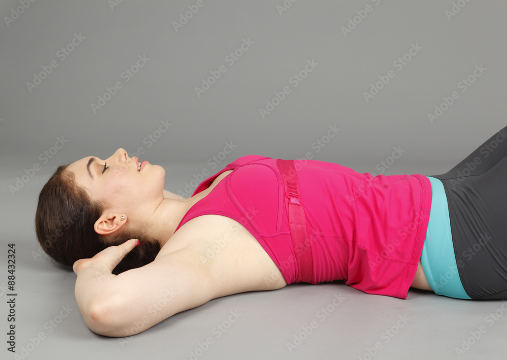 Fototapeta premium A young woman in exercise clothing lying on her back.