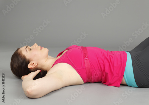 A young woman in exercise clothing lying on her back.