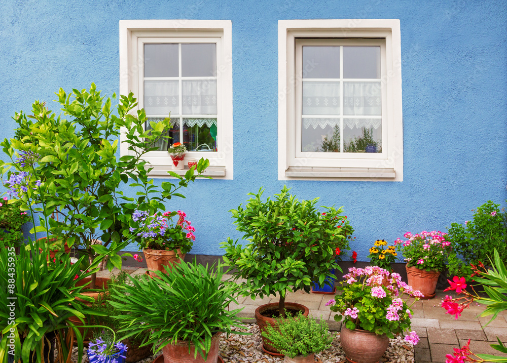 blaue Hausfront mit mediterraner Blumendekoration