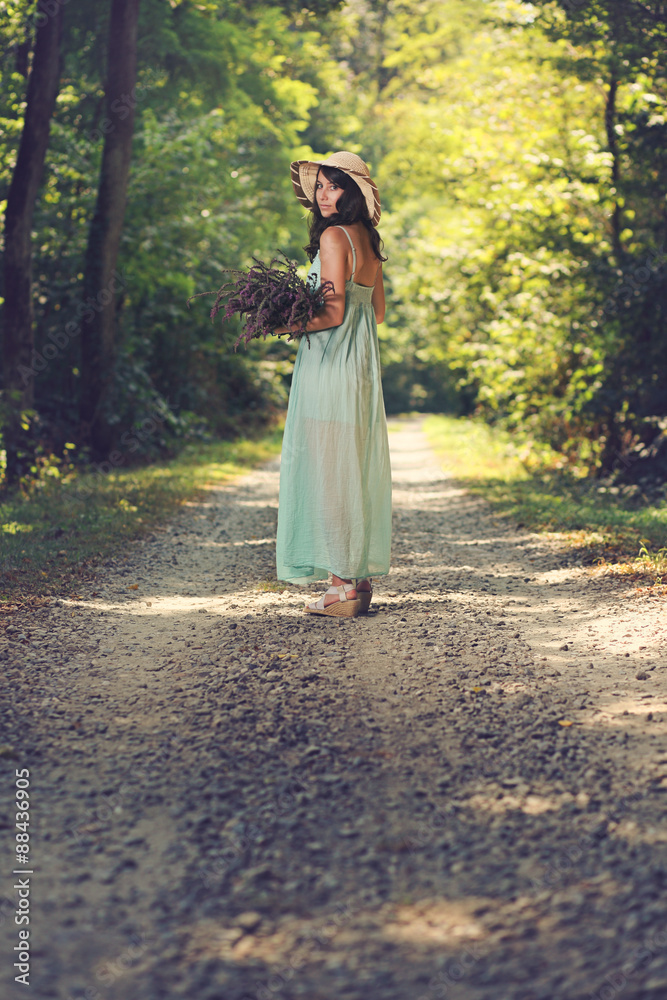 Young woman with wild flowers on a country road