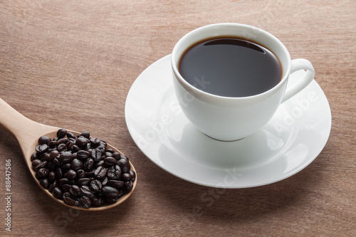 cup of black coffee and beans over wood background