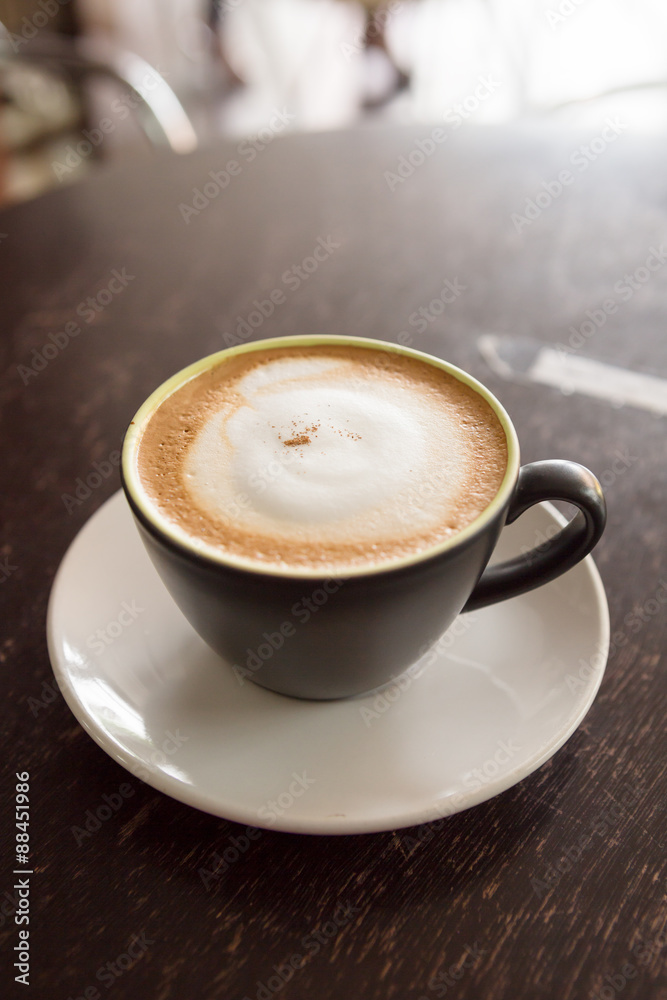 Obraz premium hot cappuccino on wood table and morning light in background