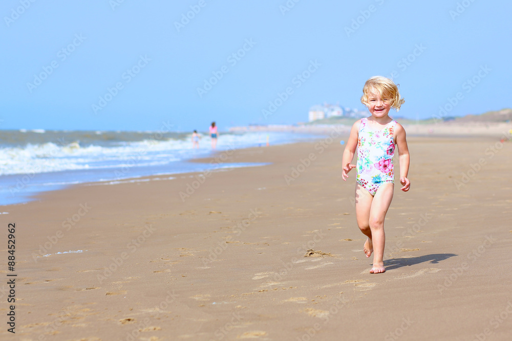 Cute active child playing on sandy beach. Happy little girl enjoying summer holidays on a sunny day. Family with young kids on vacation at the North Sea coast. Cute active child playing on sandy beach. Happy little girl enjoying summer holidays on a sunny day. Family with young kids on vacation at the North Sea coast.