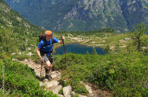 Hiker on a trail near a lake in the mountains of Ticino, Switzerland. © sanderstock