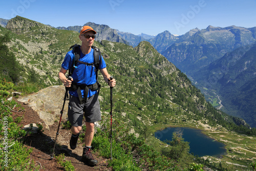 Hiker on a trail near a lake in the mountains of Ticino, Switzerland.