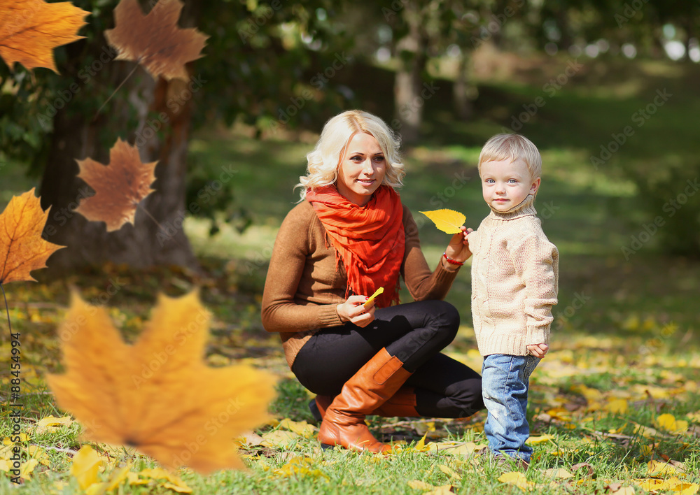 Fototapeta premium Happy mom and child playing together in warm autumn day, flying